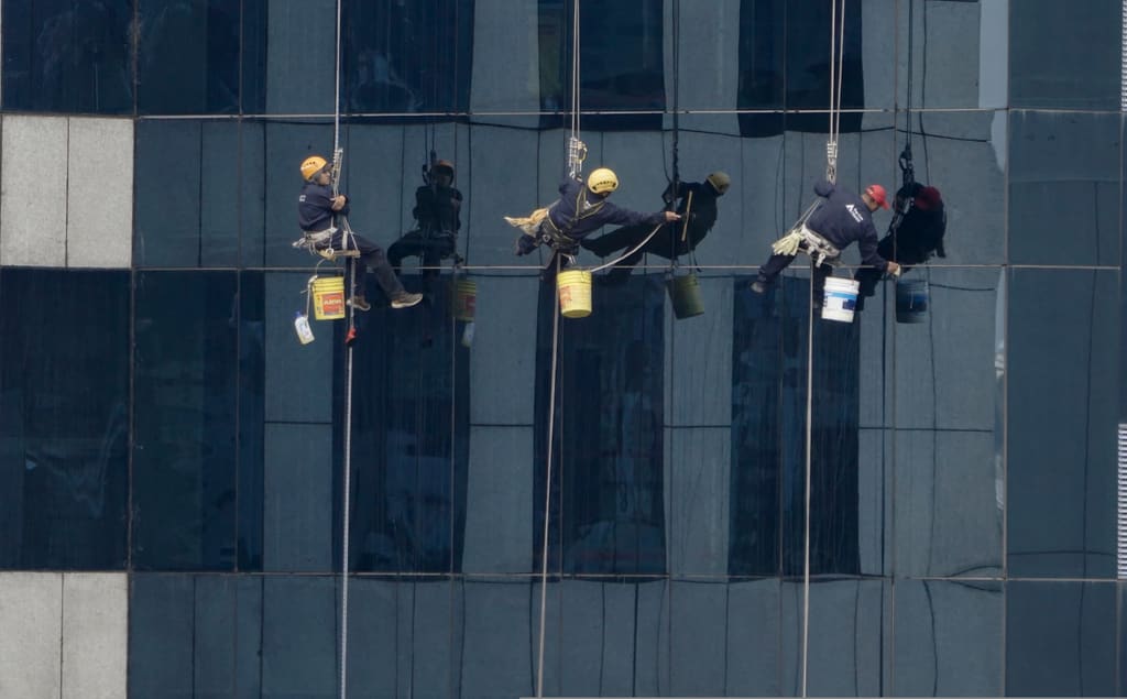 Equipo profesional de limpieza de cristales en fachada corporativa