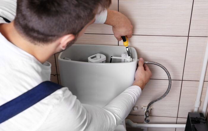 Plumber Repairing Toilet Cistern At Water Closet