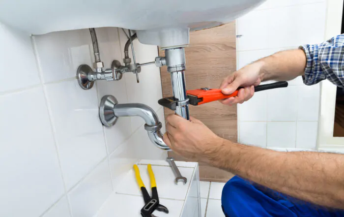 Male Plumber Fixing Sink In Bathroom